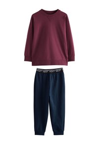 Sweat-shirt bordeaux à manches longues associé à un pantalon de jogging bleu marine à taille élastique avec l'inscription "NEXT" sur la ceinture.