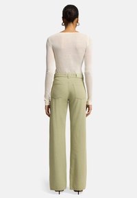 Lichte, lange mouw top in roomkleur, gecombineerd met hoge taille, wijde broek in zacht groen met stikdetails en achterzakken.
