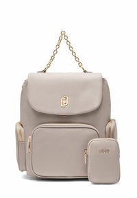 Sac à dos en nylon beige avec une poignée en chaîne dorée, fermeture à rabat, poche zippée à l'avant et une trousse assortie détachable avec logo.