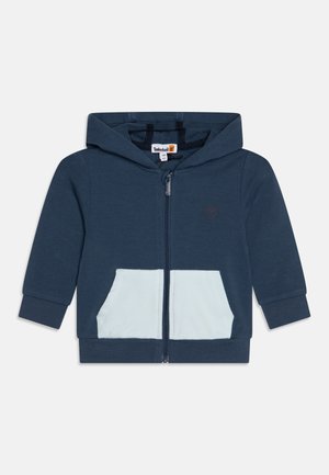 Felpa con zip blu navy con tasca azzurro chiaro, realizzata in tessuto morbido. Presenta un cappuccio e polsini a costine, con un piccolo logo sul petto.