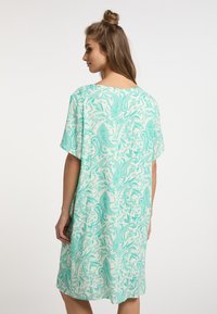 Vestido de manga corta en verde claro con un intrincado patrón de paisley. Hecho de una tela suave, de corte holgado con escote redondo y longitud hasta medio muslo.