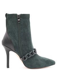 Stivaletto verde in suede con punta appuntita, cerniera laterale e tacco in pelle nera. Presenta un accento a catena spessa sulla parte superiore.