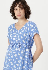 Abito da maternità blu realizzato in tessuto con un motivo floreale bianco, caratterizzato da scollatura a V, maniche corte e un dettaglio con fiocco in vita.