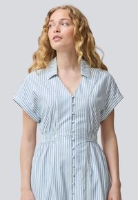 Abito a righe blu e bianche con colletto, maniche corte e apertura frontale a bottoni. Presenta una vita elastica per una vestibilità definita e un tessuto leggero.