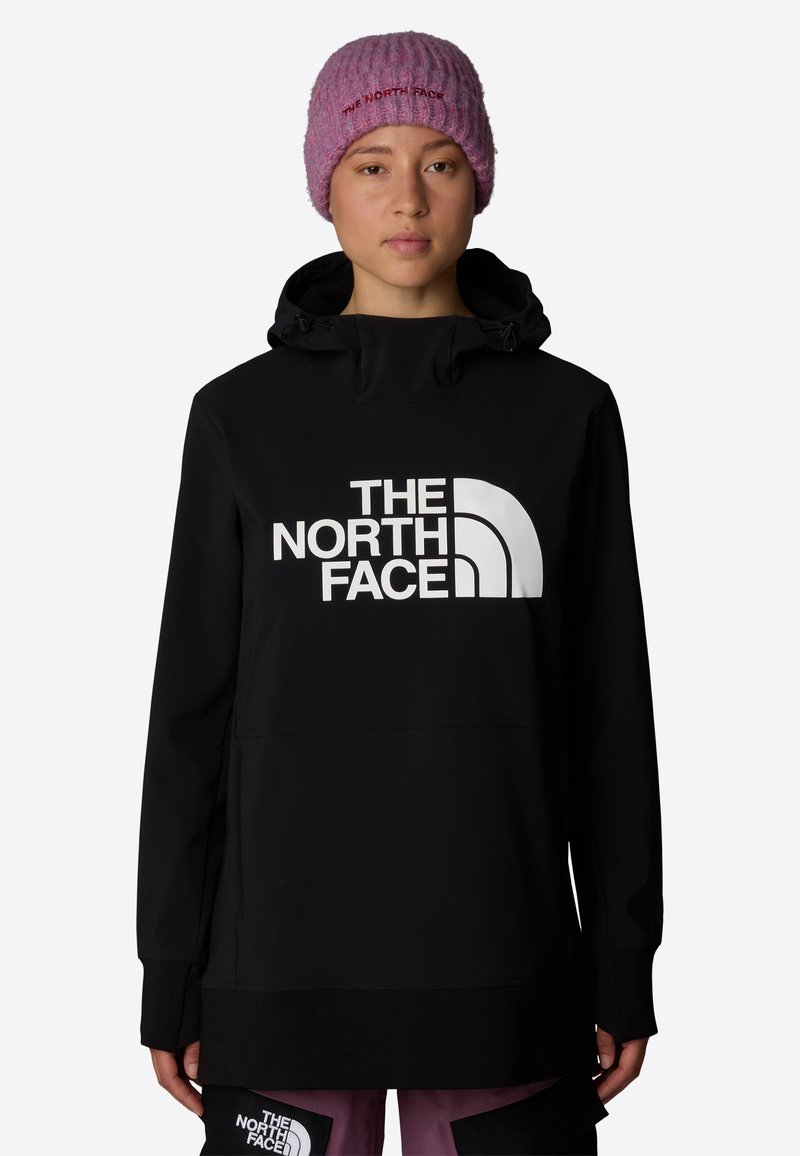 Svart pulloverjacka med en stor vit logotyp på framsidan, med huva och elastiska muddar, matchad med en rosa ribbad stickad mössa.