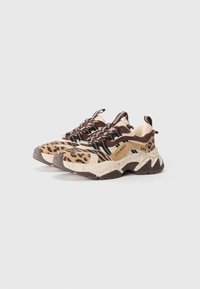 Sneakers chunky con motivi animal print beige, marrone e nero, con lacci sulla parte anteriore e suole spesse macchiate, su uno sfondo chiaro e semplice.