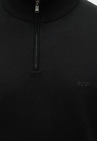 Czarny dzianinowy sweter z zamkiem sięgającym do ćwiartki i prążkowanym kołnierzem, z subtelnym czarnym logo "BOSS" wyszytym na piersi.