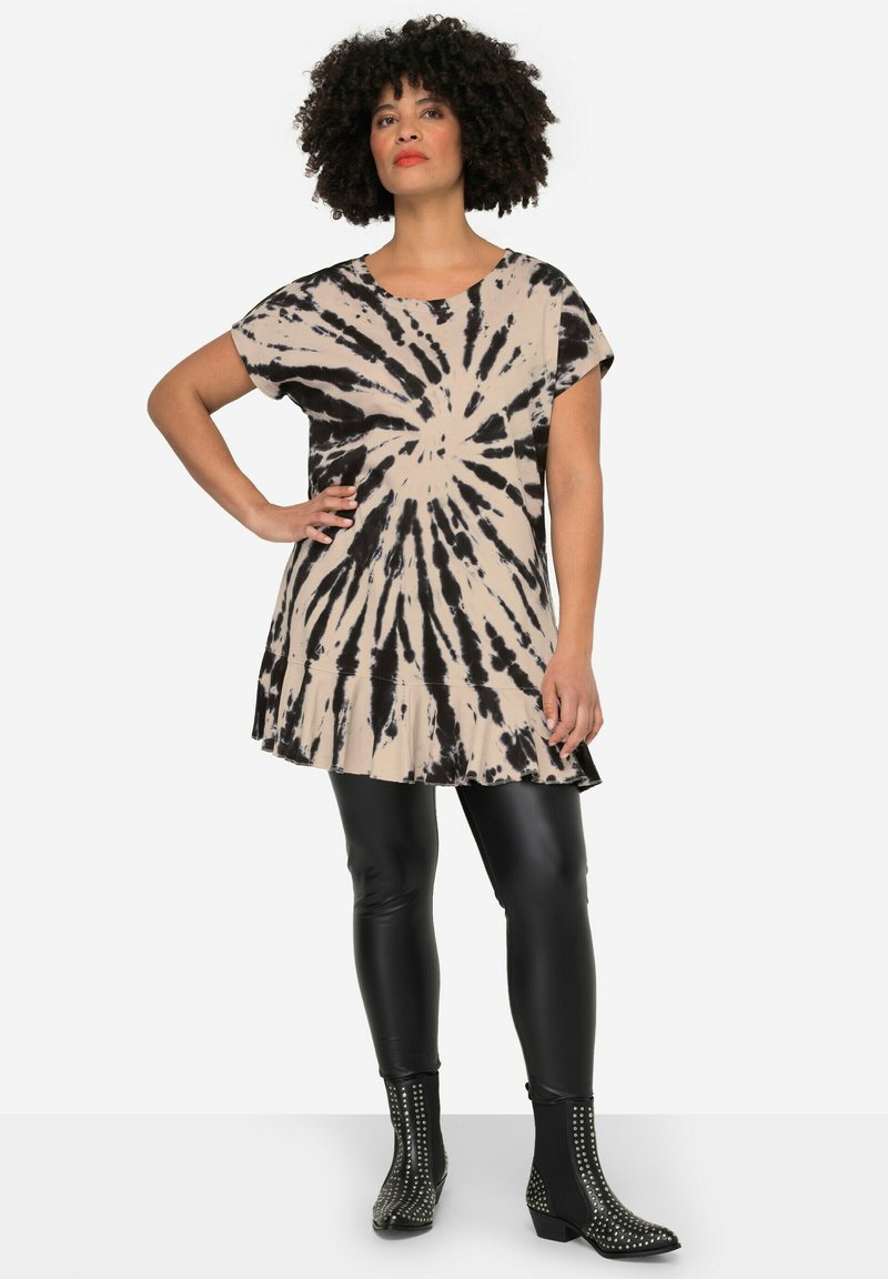 Kjole med korte ærmer og tie-dye mønster i beige og sort, med en klokkeformet kant. Sammenført med sorte læderleggins og nitter på ankelstøvler.