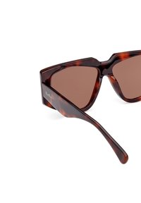 Vinklade sköldpaddsglasögon i plast med bruna linser. Böjningen av plastbågen har en geometrisk design och en slank arm med en logotypdetalj.