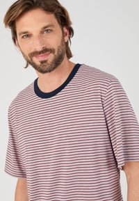 Rood en marineblauw gestreept katoenen T-shirt met een ronde hals en korte mouwen. Soepele textuur, ontspannen pasvorm en contrasterende kraag.