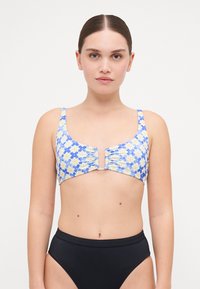 Blå blommig bikinitopp med gula blommor, med en rynkig framdel och justerbara axelband. Matchas med högmidjade svarta bikiniunderdelar.