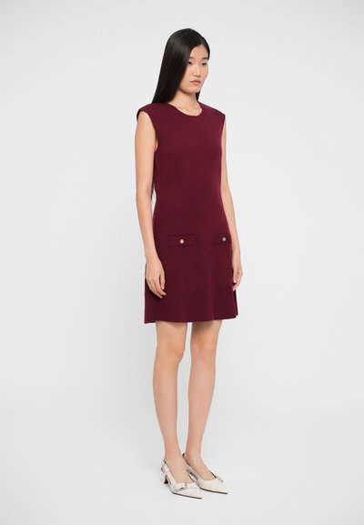 Burgundy sleeveless dress with a round neckline, two front pockets with button accents, and a fitted silhouette. Smooth knit texture.