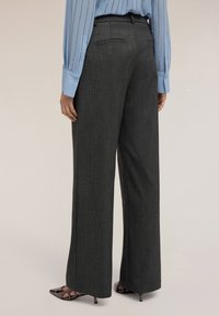 Grijze hoge taille broek met een wijd pootontwerp, gestructureerde stof en een enkele achterzak. Gecombineerd met een lichtblauw button-up shirt.