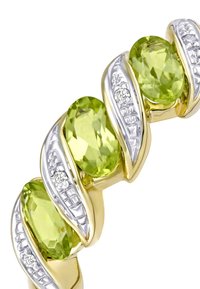 Kuld- ja hõbeselg, millel on kolm ovaalset peridootikivi, mida vahelduvad teemantide kaunistused ja keeruline disain.