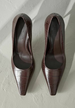 Rudi patento od cuero aukštakulniai su smailiu nosiu, turintys krokodilo tekstūrą ir lygų vidų. Sukurti elegantiškam įvaizdžiui.