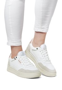 Vita sneakers med beige mocka detaljer, slät lädertextur, platta snören och en tjock gummisula. Har perforerade detaljer och logotyp.