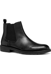 Botín Chelsea de cuero negro con paneles laterales elásticos, puntera redondeada y suela de goma texturizada, que incluye un tirador para facilitar su uso.