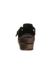 Retro sandal in suede nero sulla parte posteriore, con tacco in legno. Presenta una chiusura regolabile e un design laterale con ritagli per favorire la circolazione dell'aria.