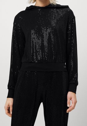 Haut à manches longues noir orné de sequins et pantalon assorti, présentant une coupe légèrement ample et des poignets resserrés.