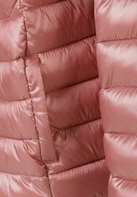 Vadderad jacka i mjuk rosa satinfinish, med horisontellt kviltat mönster, slät textur och dolda sidofickor.