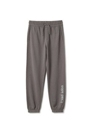 Pantalones jogger grises con cintura y puños elásticos, bolsillos laterales, cordón ajustable y texto "mala idea" en la parte inferior de la pierna derecha.