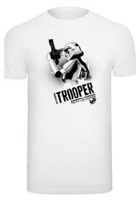 Balts kokvilnas T-krekls ar melnu grafisko attēlu, kurā redzams stormtrooper, kas tur rokā blasteri, un uzraksts "STORM TROOPER" uzrakstīts treknā fontā.