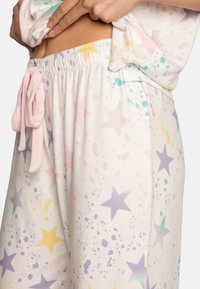 Lightweight, pastel pajama set featuring a splatter pattern with colorful stars. Includes an elastic waistband and a pink drawstring.