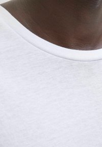 Hvid bomulds t-shirt med en glat tekstur, med rund halsudskæring og en smal ribbet hvid kant ved halsen.