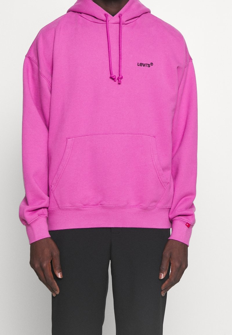 Sweat à capuche rose avec une poche kangourou à l'avant. Présente un petit logo Levi's noir sur la poitrine et des poignets côtelés aux manches.