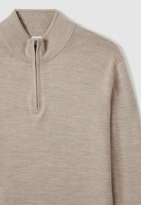 Pulover crem cu fermoar și guler înalt. Material moale, texturat, cu un model subtil de heather. Fermoar scurt pe față.