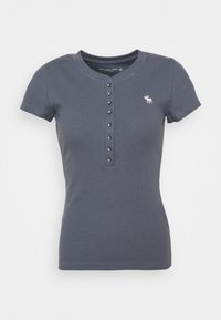 Mörkblå kortärmad t-shirt i ribbat tyg. Har rund hals och en knappslå med sex metallknappar. Litet broderat logotyp.