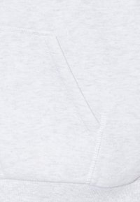 Vaaleanharmaa huppari, jossa on pehmeä ja teksturoitu kangas, kenguruntasku ja resorit hihansuissa. Saumauskoristeet ovat näkyvissä, korostaen sen muotoilua.