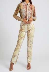 Chemise à imprimé python avec un design à boutons ; tissu doux et transparent. Pantalon assorti ajusté avec des détails en sequins dans des tons dorés et beige.