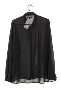 Camicia nera trasparente a maniche lunghe con collo, polsini con bottoni e una forma fluida, appesa a un gancio.