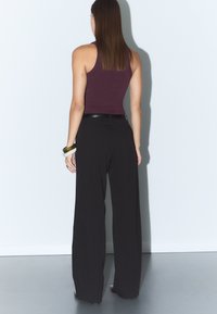 Maroon utanärmad topp kombinerad med svarta vida byxor, med en mjuk textur och en enkel design. Minimalistisk stil utan synliga mönster.