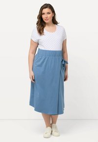 Abito di cotone con parte superiore bianca a pois blu navy e gonna blu. Include un dettaglio con cravatta in vita, con un taglio fino al ginocchio e maniche corte.