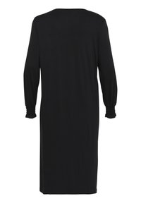 Vestido negro de manga larga. Cuello redondo, textura suave. Puños fruncidos con detalle de volantes. Ajuste a la altura de la rodilla. Diseño simple y minimalista.