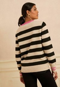 Pulover breton din lână bej și neagră, cu accente roz la guler și mansete. Proiectat cu o croială lejeră și textură ribbed.