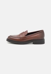 Mocassin en cuir marron avec un bout arrondi, un design à double piqûre et un style sans lacets. Il est doté d'une semelle en caoutchouc noir texturé pour le confort.