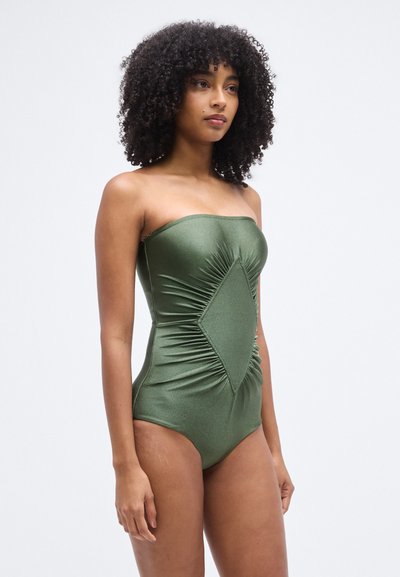 Πράσινο, ολόσωμο μαγιό χωρίς τιράντες από γυαλιστερό υλικό. Διαθέτει διαγώνιες πιέτες και διαμάντι σχήματος σχέδιο στο μπροστινό μέρος.