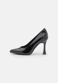Zapato de tacón alto de charol negro con punta afilada y tacón bloque escultural, con un acabado liso y brillante.
