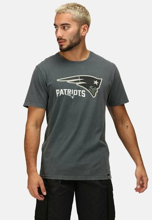 Grå bomulds t-shirt med "Patriots" logo i hvid og sort, med rund hals og korte ærmer. Casual fit, minimal tekstur.