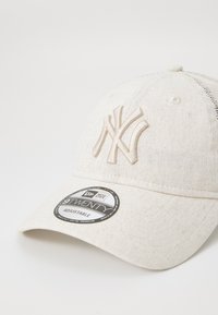 Regulējams beigē šūpuļa cepures ar izšūtu NY logo. Iezīmēts ar teksturētu audumu un izliekto vizieri. Uz etiķetes ir redzama "9TWENTY" zīmola nosaukums.