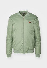 Giacca bomber verde chiaro realizzata in tessuto morbido, con zip frontale, polsini a coste e una piccola patch con logo sul petto.