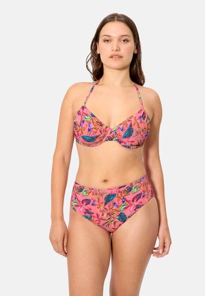 Mujer con bikini de estampado floral rosa, top halter y braguitas de talle alto, posando contra un fondo liso claro.