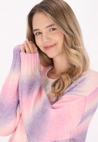 Stickad cardigan i rosa och lavendel-gradiant, med ribbade manschetter och en lös passform. Mjuk textur med synligt stickat mönster.