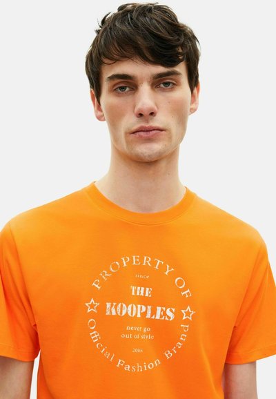 Oranje katoenen t-shirt met een ronde witte grafische print met tekst in het midden, korte mouwen en een ronde halsontwerp.