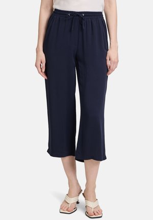 Navy culotte pants with an elastic waistband and drawstring. Soft fabric with a smooth texture, cropped length, and wide leg design.