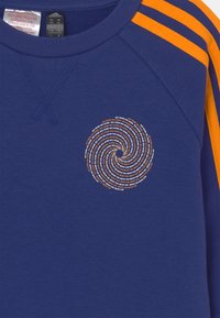 Sudadera azul marino con rayas naranjas en los hombros, con un gráfico en espiral en el pecho en color naranja y texto blanco. Tela suave de algodón.