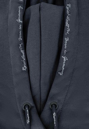 Donkergrijze hoodie van zacht materiaal, met een trekkoordsluiting met zwarte uiteinden en geborduurde tekst langs de randen.